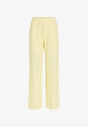 Pantalon large jaune clair avec motif perforé en forme de losange, taille élastique et texture de tissu douce.