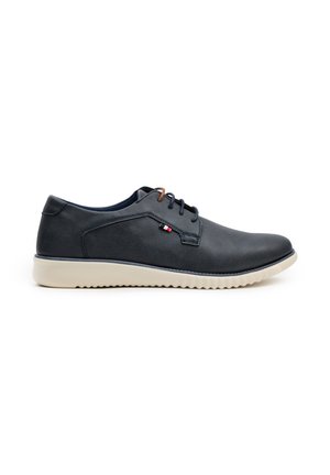 Zapato de cuero negro con una superficie lisa, diseño de cordones, suela de goma beige y pequeños acentos de logo en el costado.