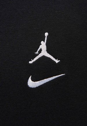 Svart stoff med hvit brodert Jumpman-logo og Nike-svush, som viser glatt tekstur og distinkt design.
