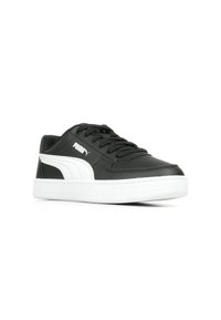 Baskets en cuir noir avec semelle en caoutchouc blanche, équipées de lacets noirs et du logo Puma sur le côté. Texture lisse avec des accents blancs contrastants.