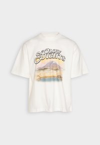 Camiseta de algodón blanca con mangas cortas, que presenta un gráfico de un paisaje montañoso y el texto "GLOW LIGHTS" en letras negras y amarillas.