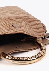Una borsa a tracolla in corduroy color cappuccino parzialmente aperta, che rivela un interno liscio. Un manico in metallo dorato lucido con il marchio è visibile sul lato.