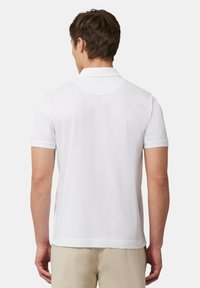 Polo bianco con colletto classico, maniche corte e una texture liscia. Il retro presenta una silhouette aderente con orlo dritto.