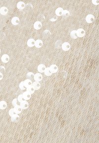 Beiger Stoff mit Netzstruktur, verziert mit verstreuten irisierenden Pailletten in verschiedenen Größen, die eine schimmernde Oberfläche erzeugen.