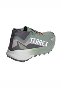 Chaussure de trail légère verte avec une tige en mesh texturé, des accents noirs, un grand logo "TERREX" blanc, et une semelle en caoutchouc texturé pour une meilleure traction.