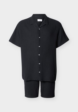 Cămașă neagră pentru bărbați, cu nasturi, mânecă scurtă, asortată cu pantaloni scurți negri, material ușor texturat și guler clasic.