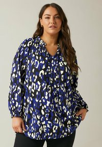 Blusa ampia con un motivo a stampa tigre blu, nero e bianco. Tessuto testurizzato con scollatura arricciata e maniche lunghe.