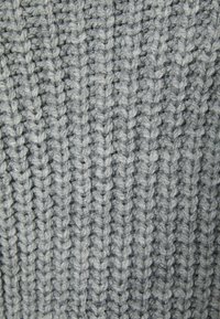 Gros plan sur un tissu tricoté gris montrant un motif côtelé détaillé et une texture de fil épais.