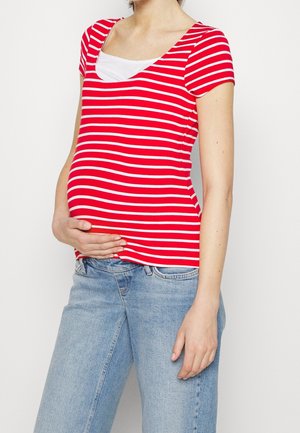 Top de maternidad de rayas rojas y blancas con mangas cortas, escote en pico y silueta ajustada, combinado con jeans azul claro.