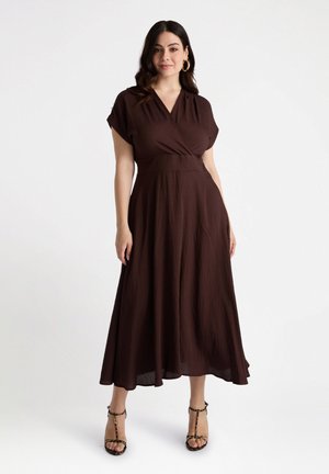Brown wrap dress made of lightweight fabric, featuring short sleeves, a fitted waist, and a flowing skirt that reaches mid-calf.