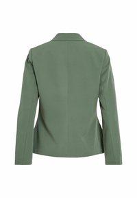 Blazer verde a medida con cuello de muesca, hombros estructurados y mangas largas. Tela suave y diseño limpio y minimalista.
