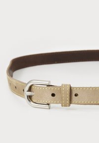 Ceinture en suède beige avec des coutures jaunes, une boucle en métal argenté et plusieurs trous pour l'ajustement. Texture douce et design arrondi.