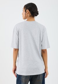 Gray unisex t-shirt made of soft fabric, featuring short sleeves, a relaxed fit, and a round neckline. Visible stitching detail at hem.