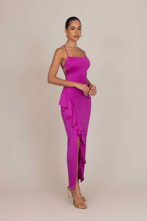 Abito da sera fucsia con spalline sottili, una ruga laterale e uno spacco fino alla coscia; realizzato in un tessuto liscio; accentuato da scarpe con tacco dorate.