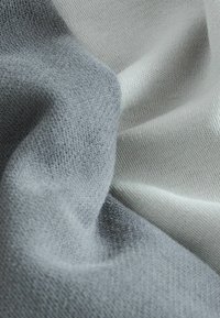 Zachte stof in lichtgrijs en wit, met een gladde textuur en fijn gebreid patroon, met zachte plooien en vallende plooien.