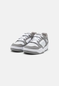 Sneakers grigi e bianchi con tomaia in pelle testurizzata e rete, punta perforata, lacci piatti e suola in gomma spessa.