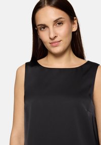 Czarny bezrękawnik o gładkiej fakturze, z okrągłym dekoltem i luźnym krojem, cechujący się minimalistycznym designem bez widocznych wzorów czy ozdób.