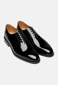Schwarze Lacklederschuhe mit glatter Oberfläche, runder Zehenform, sechslöchriger Schnürung und kleinem Blockabsatz.