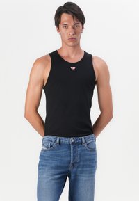 Zwarte mouwloze tanktop met een ronde halslijn, voorzien van een klein rood logo-detail. Draag het met blauwe denim jeans voor een casual look.
