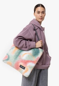 Plyšová taška s mnoha barvami vyrobená z měkké látky s kombinací pastelově zelených, růžových a oranžových vírů. Má černé logo Eastpak.