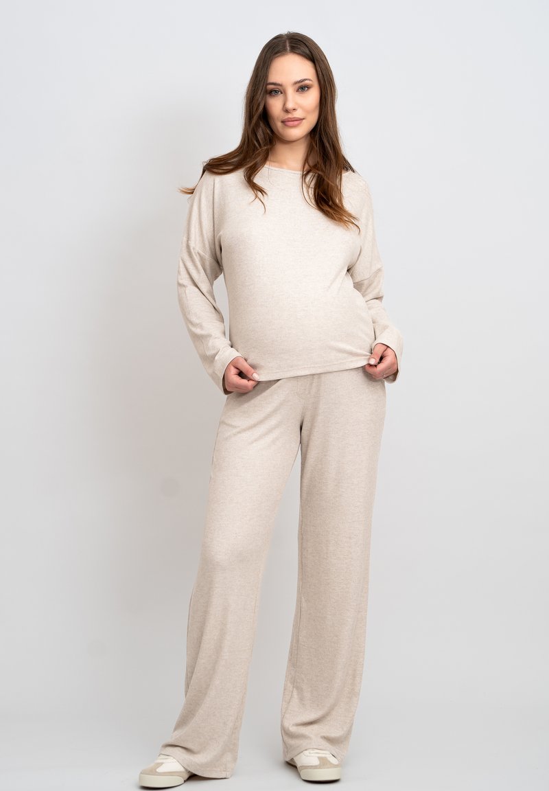 Hellbeige Loungewear-Set mit einem lässigen Langarmoberteil und weit geschnittenen Hosen. Weicher, strukturierter Stoff mit einem schlichten Design.