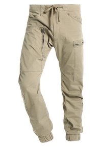Pantaloni cargo marrone chiaro con vita regolabile, tasche sulla coscia con zip, dettagli cuciti e polsini elastici alle caviglie.