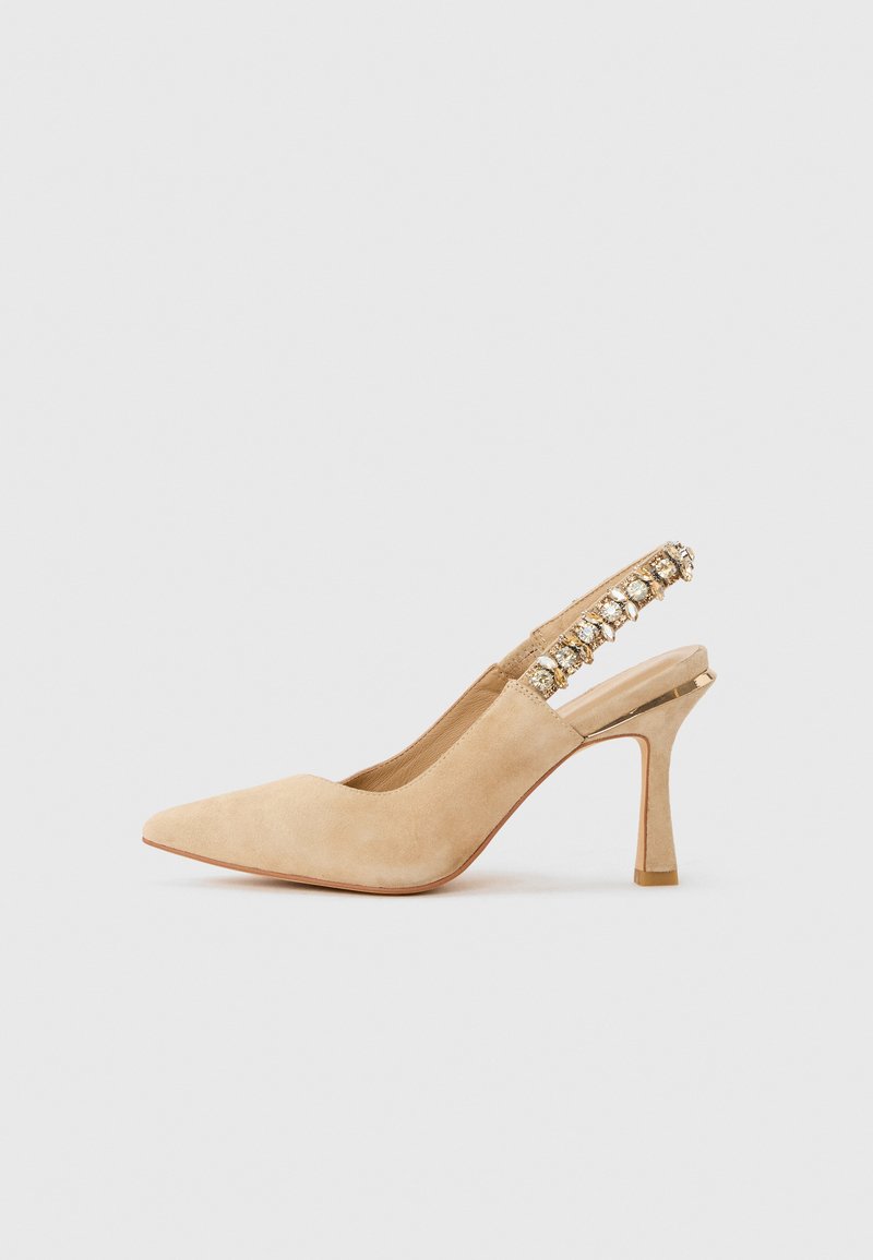 Μπεζ δερμάτινο γόβα μυτερό με ψηλό τακούνι slingback, διακοσμημένο με λουράκι με πολύτιμους λίθους και λεπτό τετράγωνο τακούνι σε ανοιχτό φόντο.