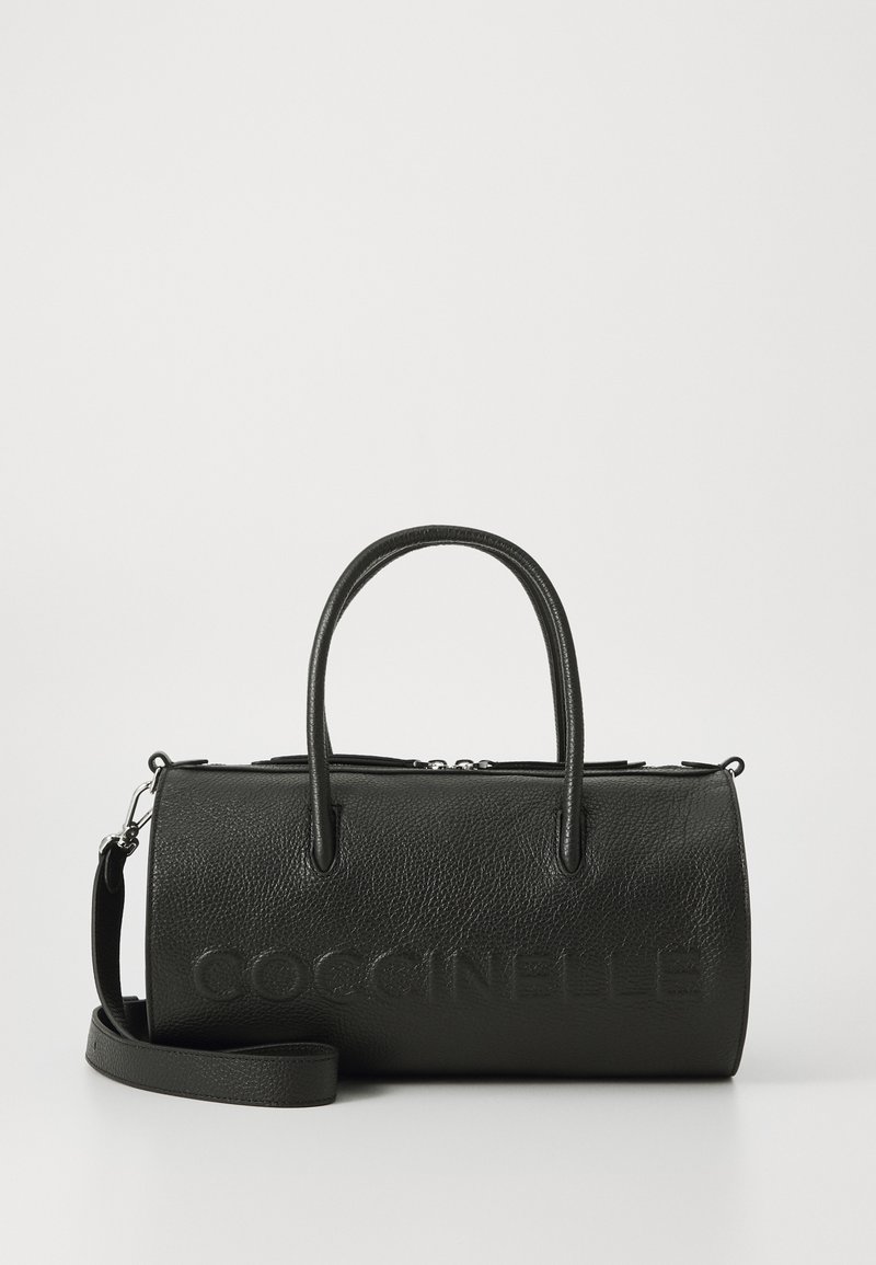 Sac à main cylindrique en cuir texturé noir avec doubles poignées, bandoulière amovible et logo « COCCINELLE » embossé sur le devant.