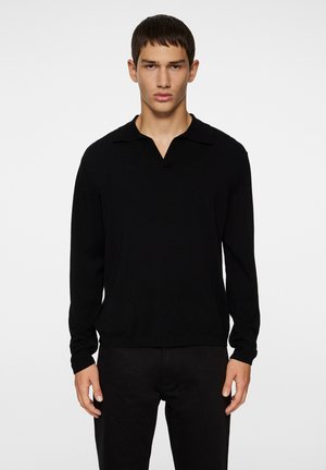 Schwarzer Pullover mit V-Ausschnitt und kurzem Kragen. Lange Ärmel und gerippte Bündchen. Hergestellt aus einem glatten, weichen Stoff. Einfaches Design.