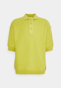 Polo shirt a maniche corte e colletto di colore giallo con tre bottoni su uno sfondo bianco.