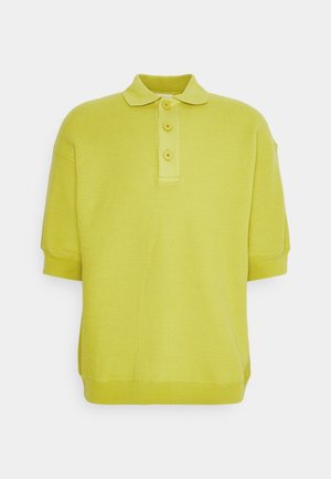 Geel kortebloesem gebreid poloshirt met een kraag en drie knopen op een witte achtergrond.