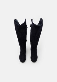 Bottes hautes en daim noir à la texture lisse, avec un léger effet froissé en haut et des fermetures éclair sur les côtés.