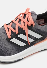 Heren sneakers met een grijze mesh bovenkant, oranje veters en drie witte strepen aan de zijkant. Heeft een gestructureerde afwerking en een rubberen zool.