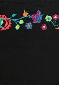 Svart stoff med fargerik blomsterbroderi i rødt, rosa, blått, oransje og grønt garn med varierte stingmønstre og former.