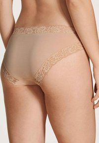 Beige Unterwäsche mit Spitzenverzierung, die ein glattes, nahtloses Design bietet, mit floralen Spitzenakzenten am Bund und an den hinteren Kanten.
