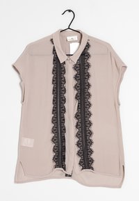 Light beige short-sleeve blouse with a lace panel down the center featuring black floral patterns and a button-up collar.