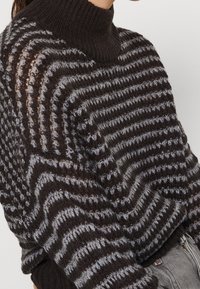 Maglione a righe marrone scuro e grigio, lavorato a maglia con collo alto, realizzato in un tessuto strutturato e dalla vestibilità ampia, con polsini a coste.