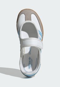 Biele a sivé topánky s modrým pruhom. Obsahujú suchý zips, mäkkú textúru, zaoblenú špičku a gumovú podrážku. Interiér ukazuje značku.