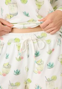 Loungewear-set med ett vitt tyg med ett färgglatt mönster av cocktails och kaktusar. Inkluderar justerbar dragsko i midjan.