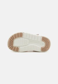 Sulan har en segmenterad design med en vit bas och strukturerade ljusbruna och beige accenter för förbättrat grepp och traction.