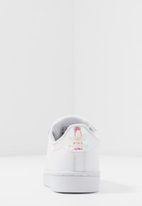 Sneaker bianca con tomaia in pelle texturizzata, accento iridescente sul tallone e suola in gomma bianca. Design semplice e a scarponcino basso.