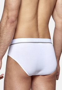 Weiße Baumwollslips mit einem grauen Akzentbund, auf dem "IMPETUS" steht. Glatte Textur mit klassischem Schnitt, minimalen Nähten.