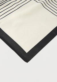 Μεταξωτό μαντήλι με κρεμ φόντο, διακοσμημένο με μαύρες διαγώνιες ρίγες και μαύρο περιθώριο. Το ύφασμα έχει λεία υφή.