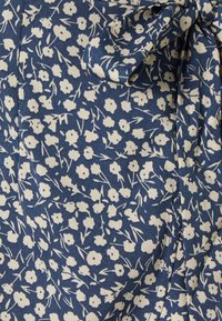 Navy fabric featuring a white floral pattern, with small flowers and leafy accents; includes a decorative bow detail.