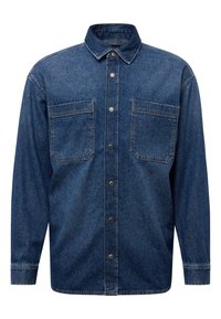 Donkerblauwe spijkerblouse met lange mouwen, knoopsluiting aan de voorkant en twee borstzakken. Heeft een traditionele kraag en subtiele stikdetails.