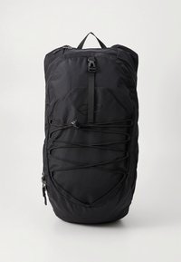 Čierny batoh s textúrovaným nylonovým vonkajškom, vybavený systémom pružného lanka na prednej strane, horným rúčkou a oddeleniami na zips.