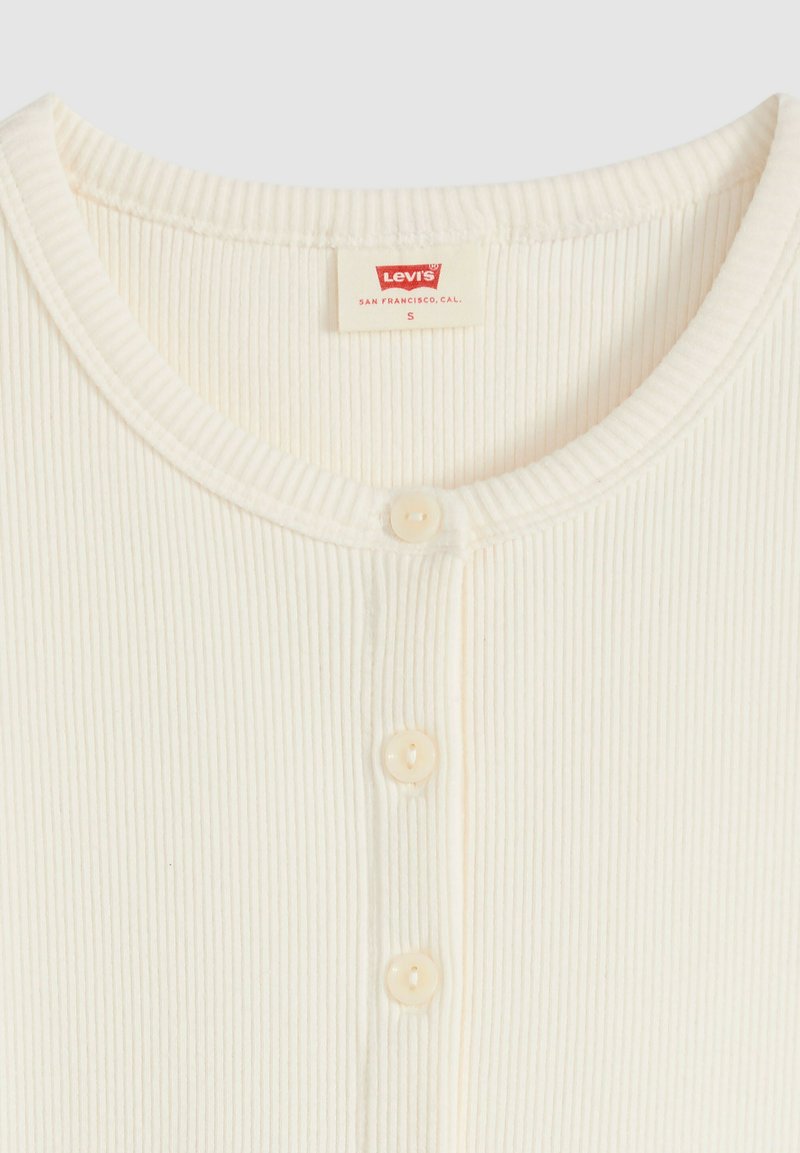 Haut en tissu côtelé crème avec col rond, trois petits boutons sur le devant et étiquette Levi's à l'intérieur du col indiquant la taille small.