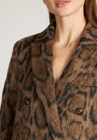 Luipaardprintjas in bruin en zwart, gemaakt van een textuurwolmix. Voorzien van een notch-kraag en twee bruine knopen aan de voorkant.