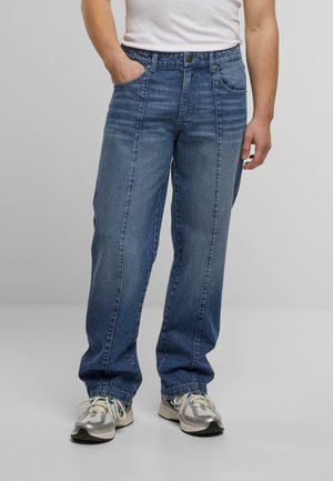 Light blue denim jeans, loose fit, two front pockets, faded texture, waistband with button closure, worn with gray sneakers.