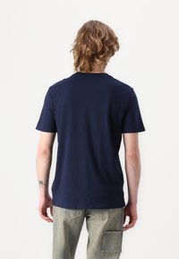 Camiseta de algodón azul marino de manga corta y cuello redondo clásico, con una textura suave y un ajuste relajado.